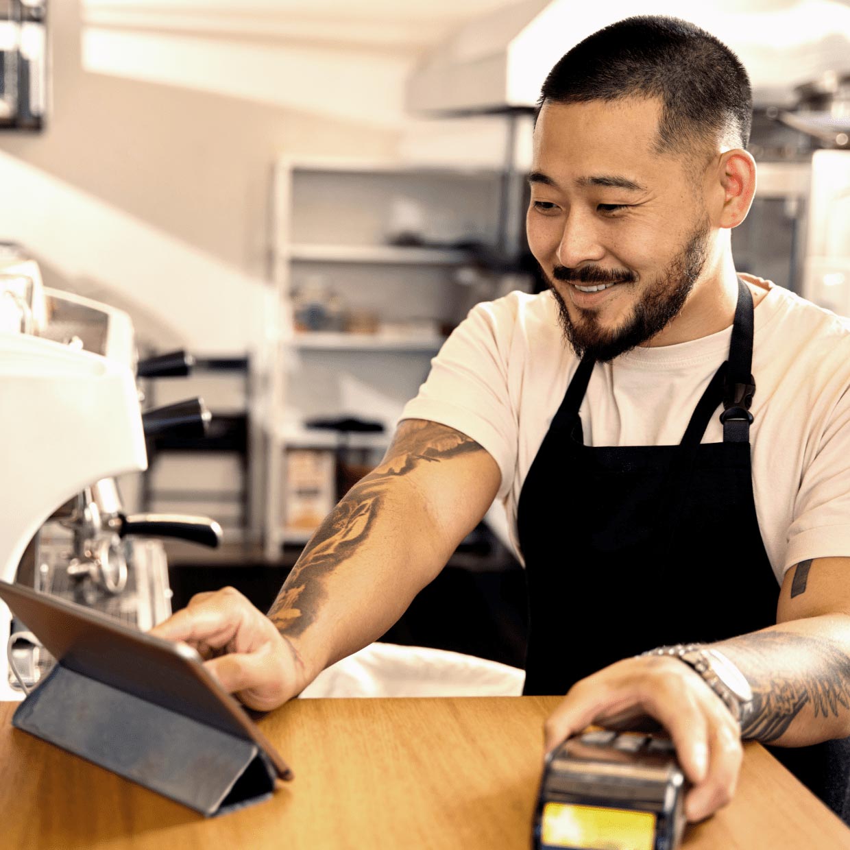 Man at café processing a payment with tablet and EFTPOS terminal