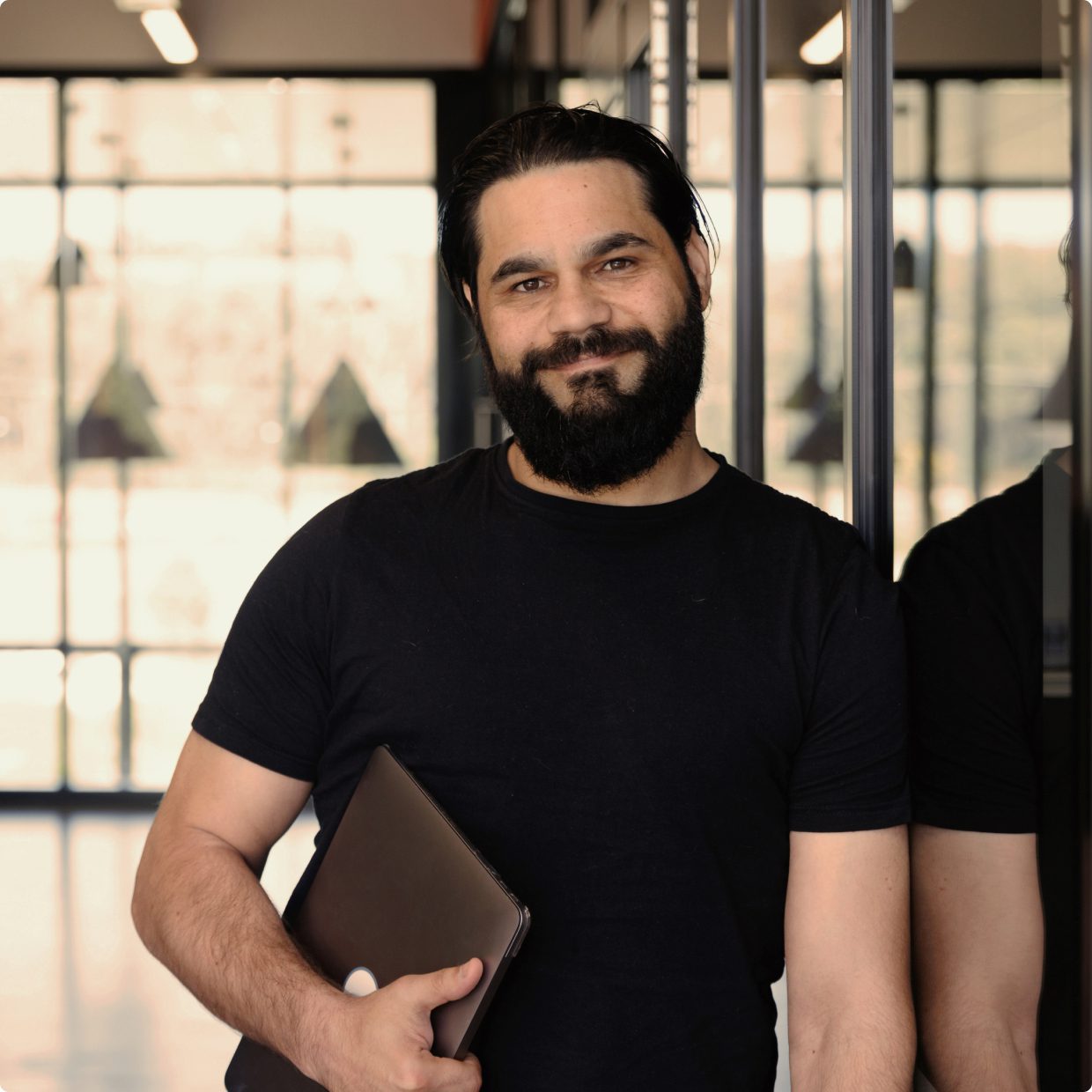 Man smiling holding a laptop under his arm