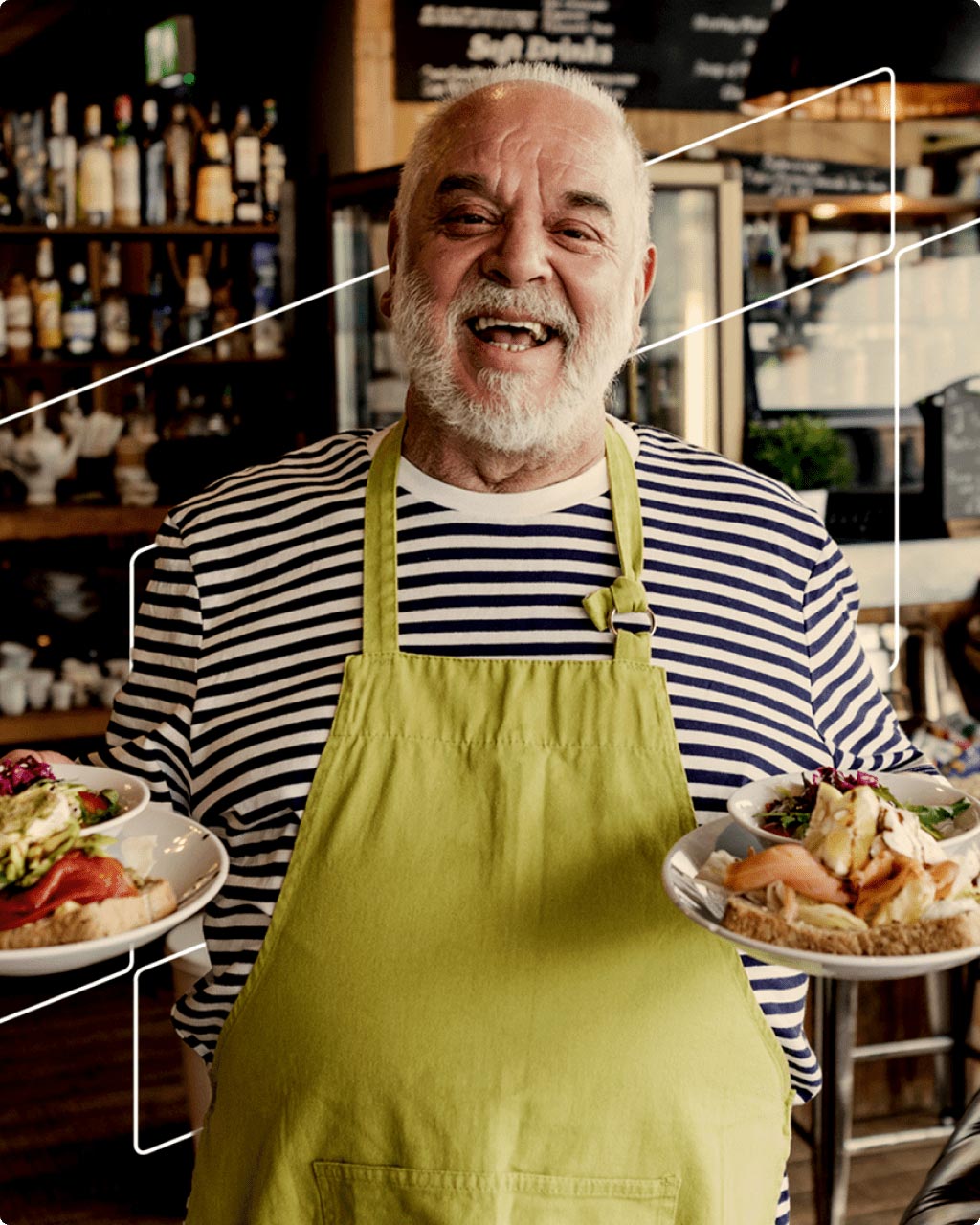 Smiling man walking with plates of food inside café