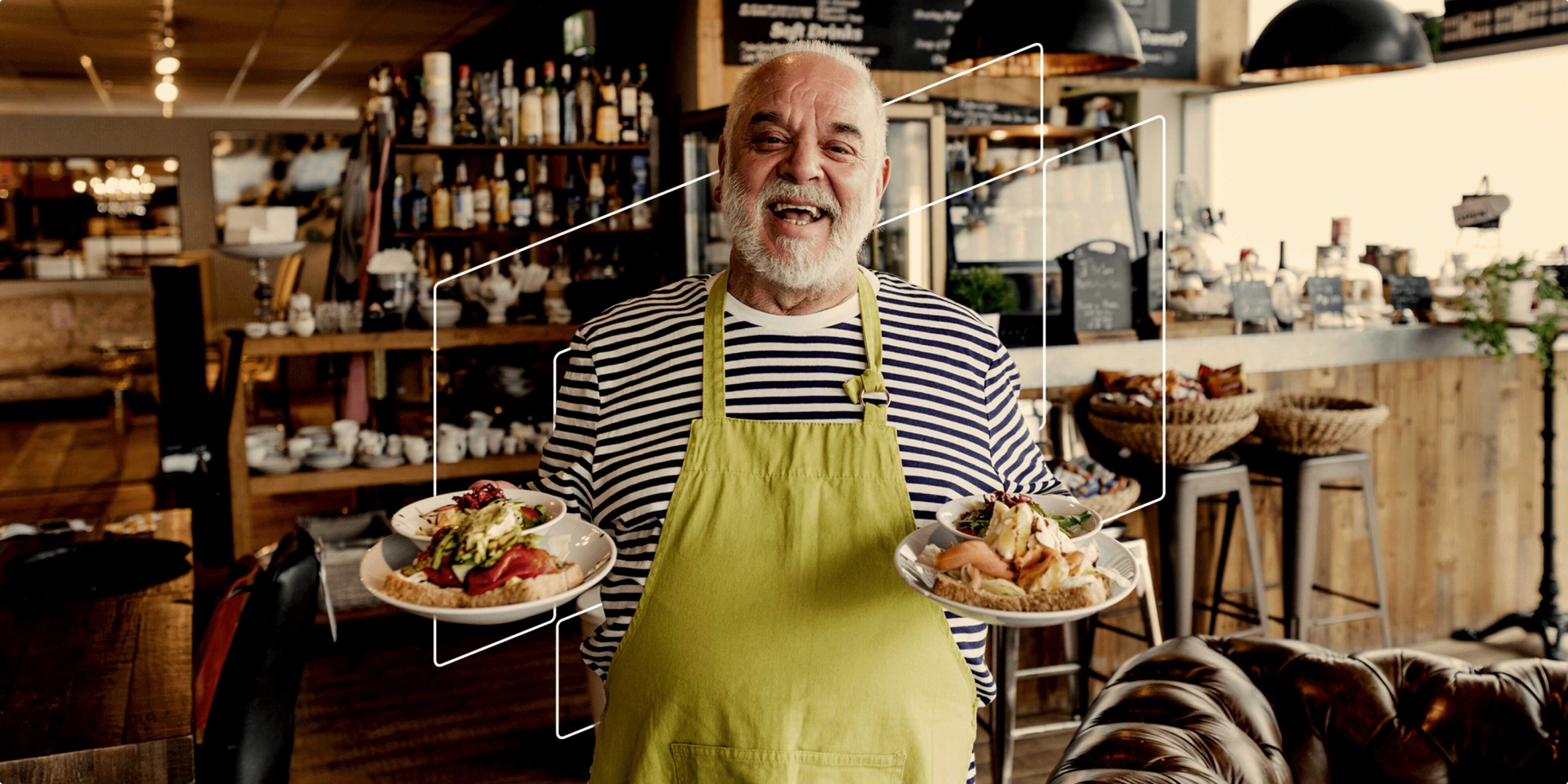 Smiling man walking with plates of food inside café