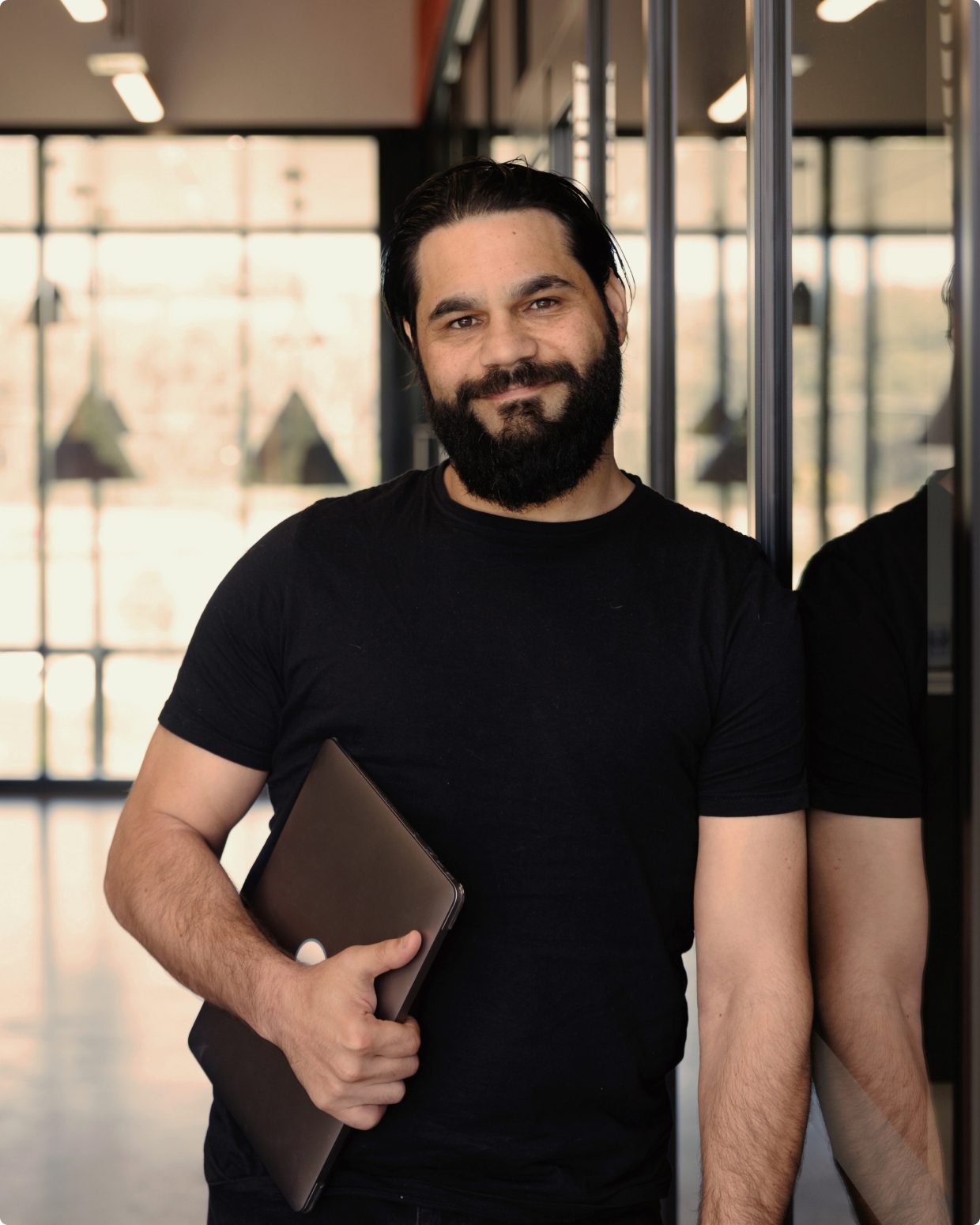 Man smiling holding a laptop under his arm