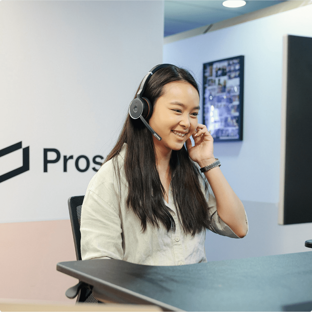 Support agent with headset at desk in office.