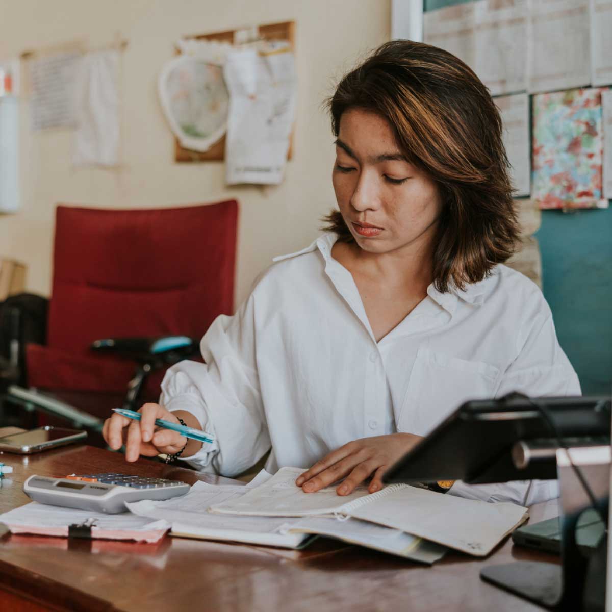 Young business owner does manual accounting using calculator and notepad