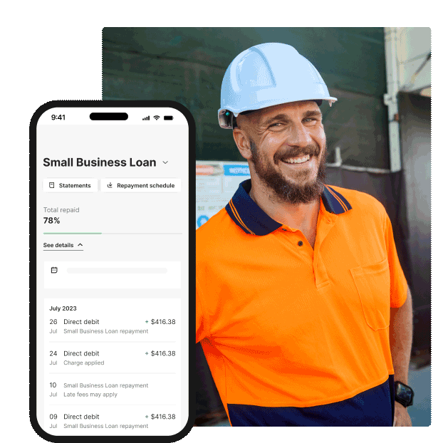 A construction worker wearing high‑visibility clothing and a hard hat, standing at a worksite next to a smartphone showing a small business loan repayment overview.