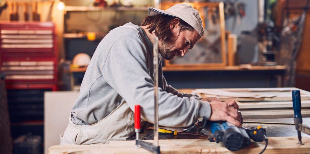 Male carpenter working on old wood in a retro vintage workshop