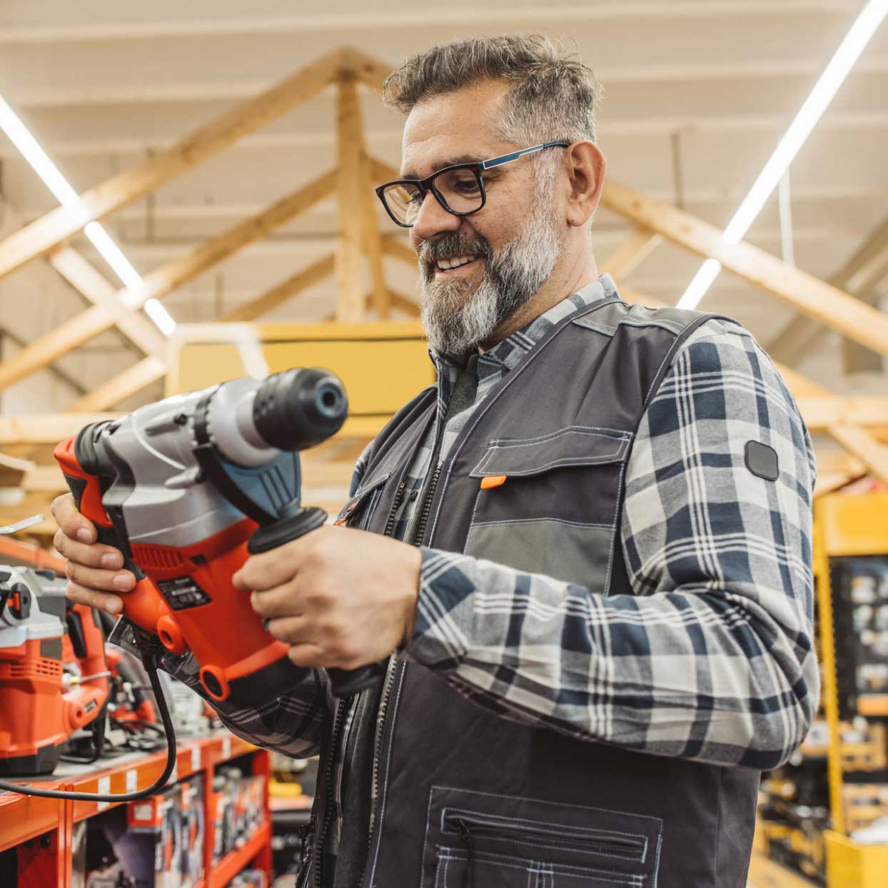 Customer examining a power tool inside a hardware store with product displays in the background.
