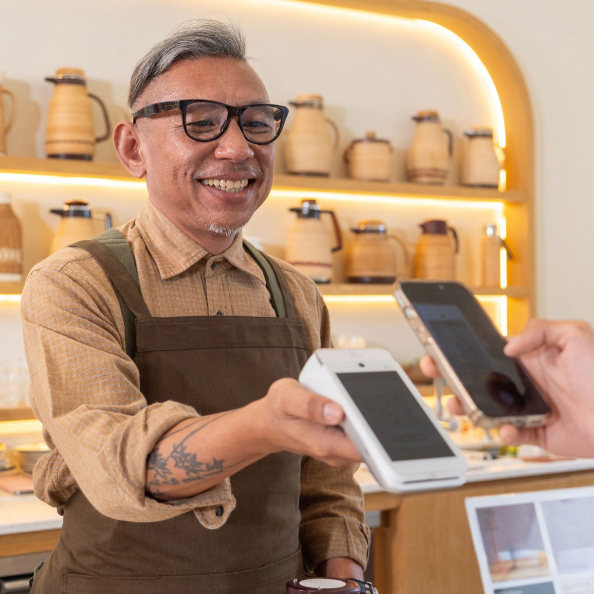 Shop keeper using terminal to accept payment from a phone
