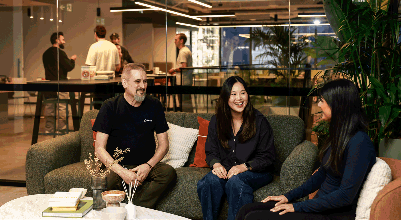Employees seated together in a casual office lounge area, collaborating and talking within a modern workplace.